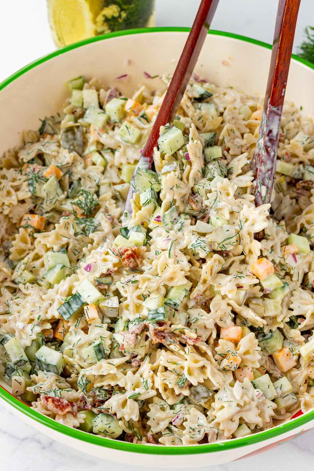 tossing dill pickle pasta salad in a large bowl