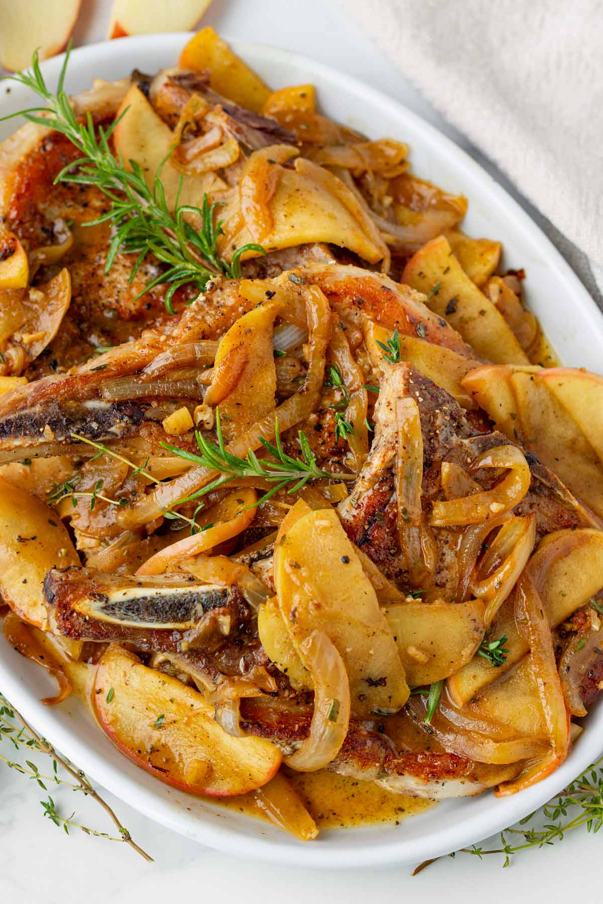 platter of bone in pork chops covered with apples and onions in a pan sauce