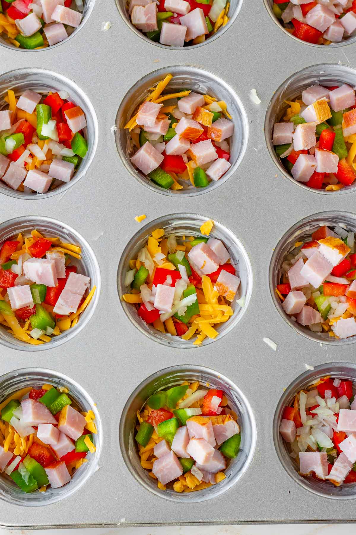 12 cup muffin pan filled with ham, cheese, peppers