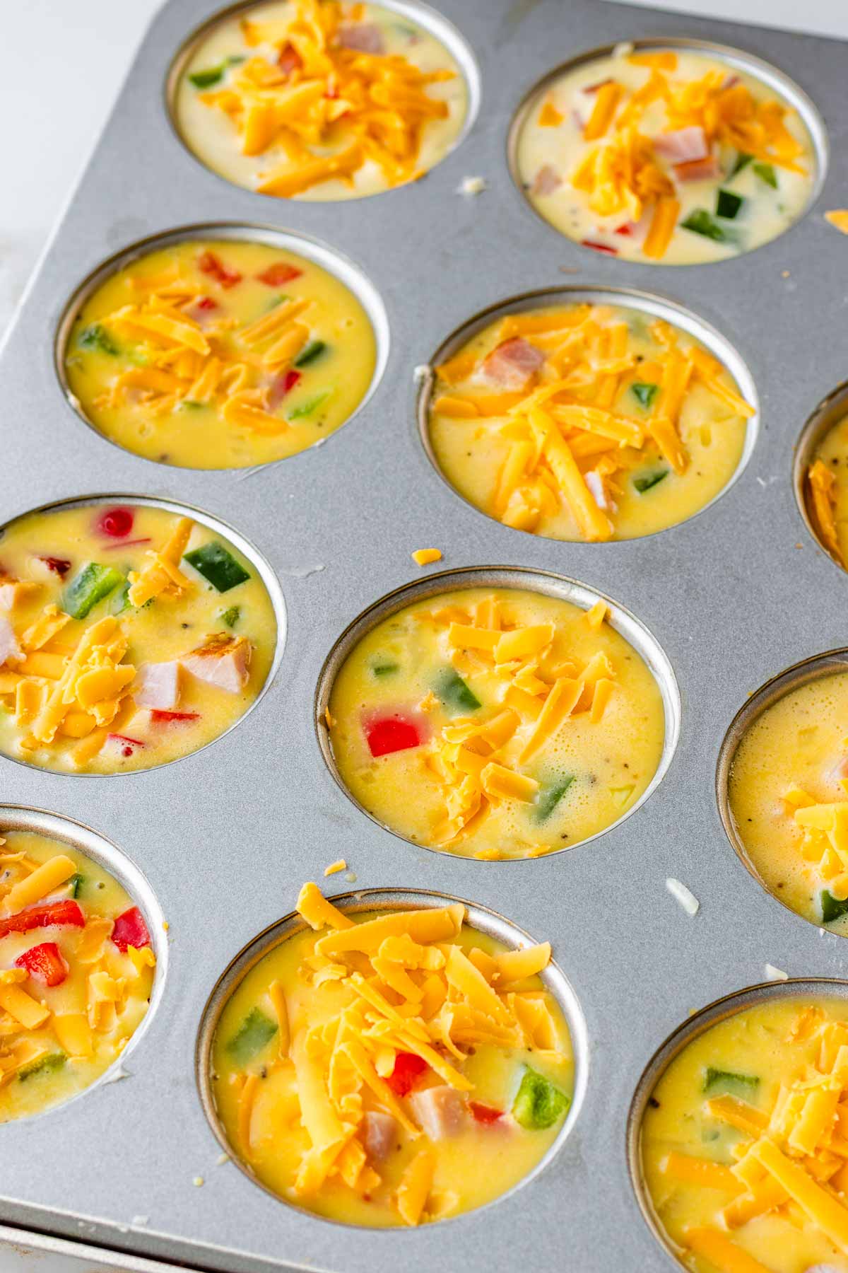 muffin pan filled with eggs and toppings