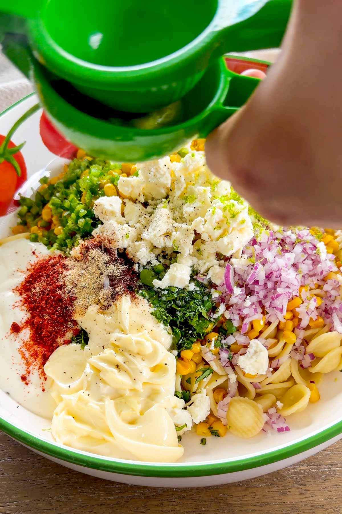 adding the dressing to the pasta salad