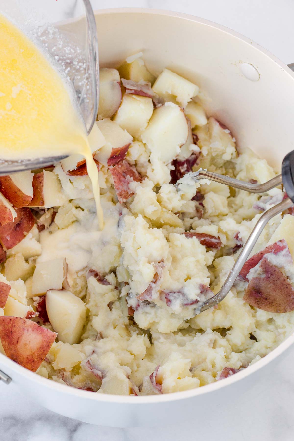 adding melted butter and cream to the cooked potatoes