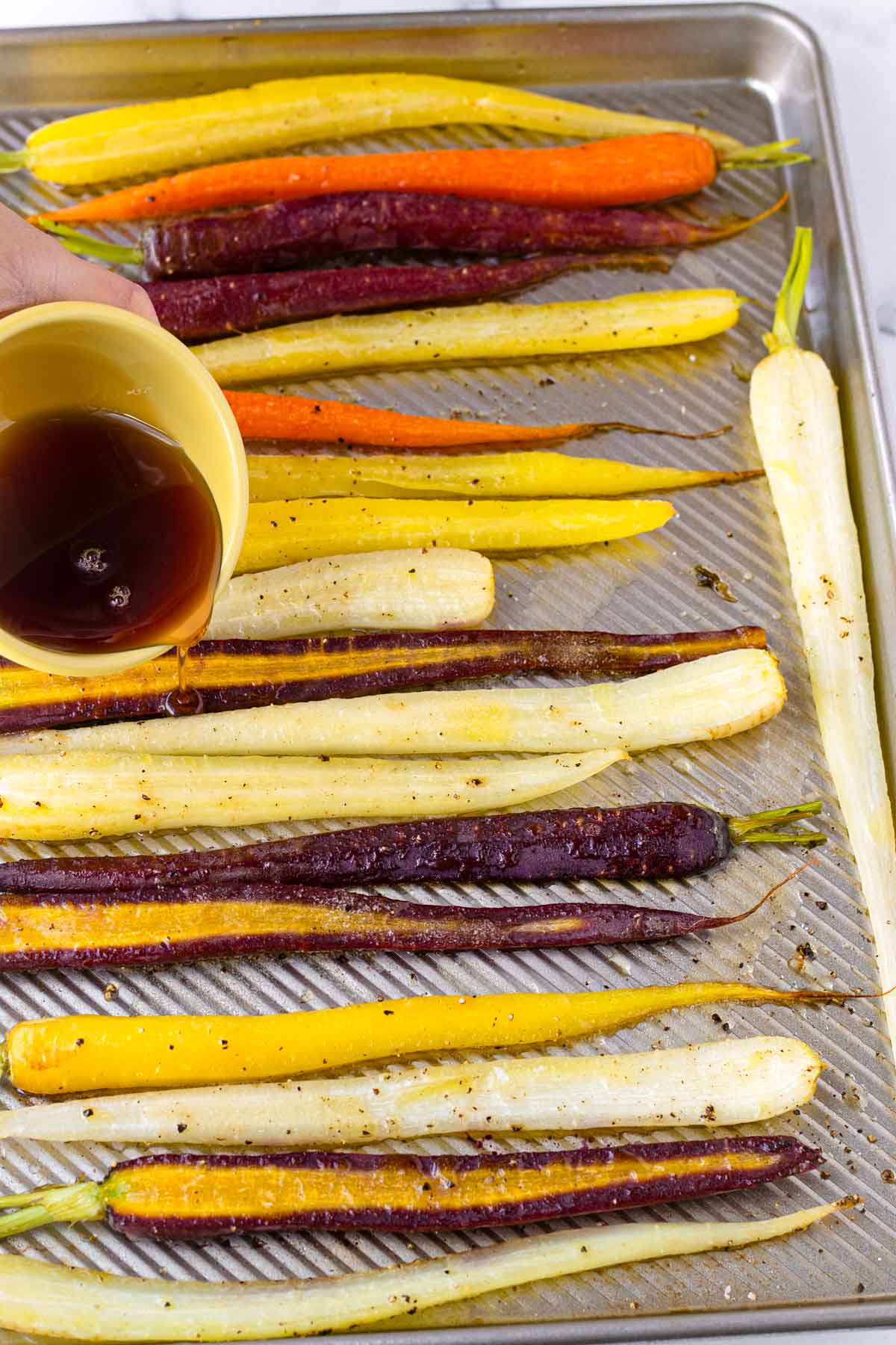 adding maple butter glaze to par-roasted carrots