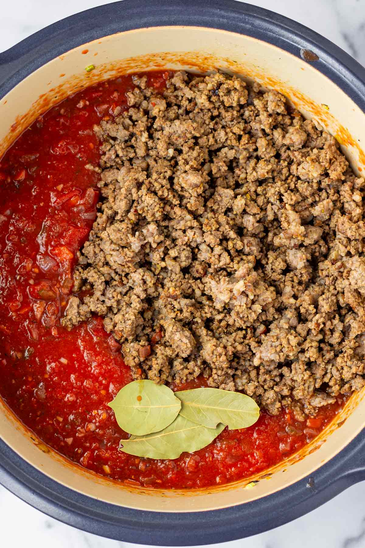 added crushed tomatoes, bay leaves, and the cooked meat