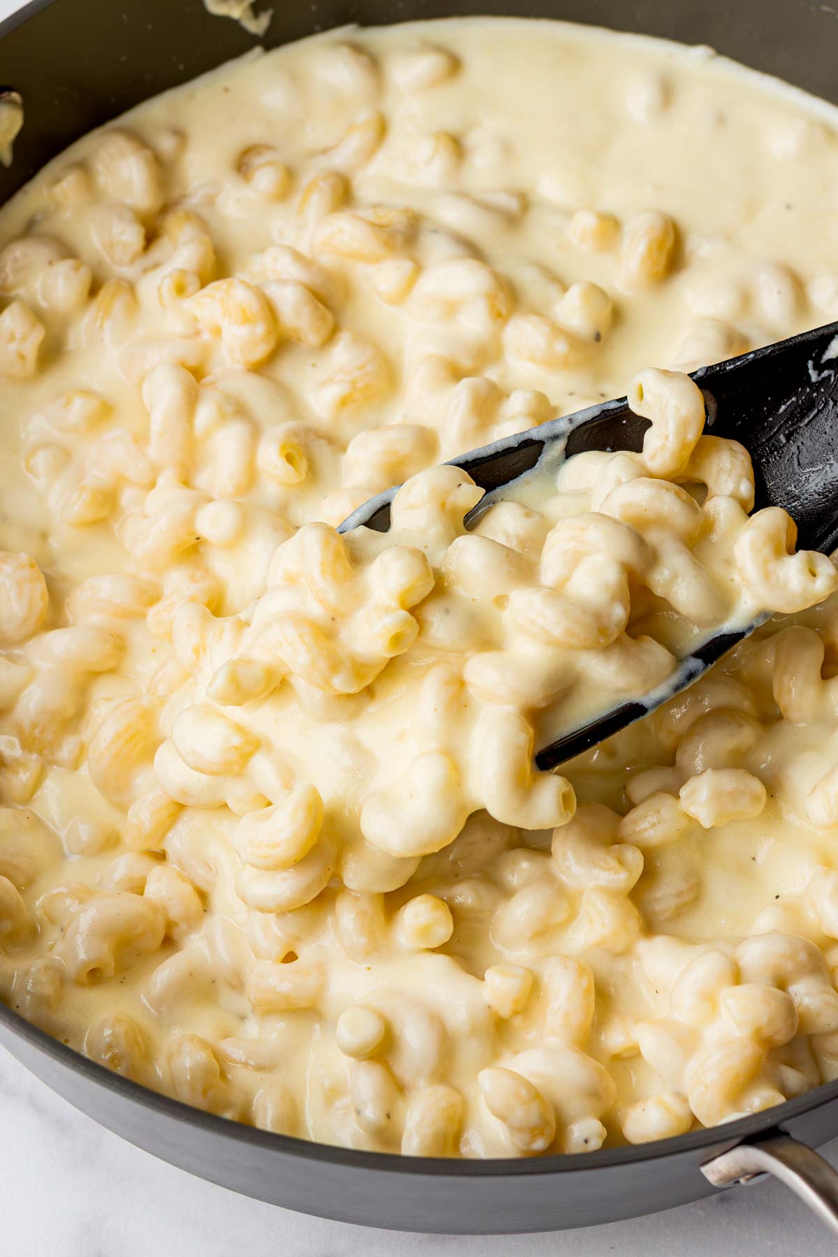 adding the cooked pasta into the cheesy mac and cheese sauce