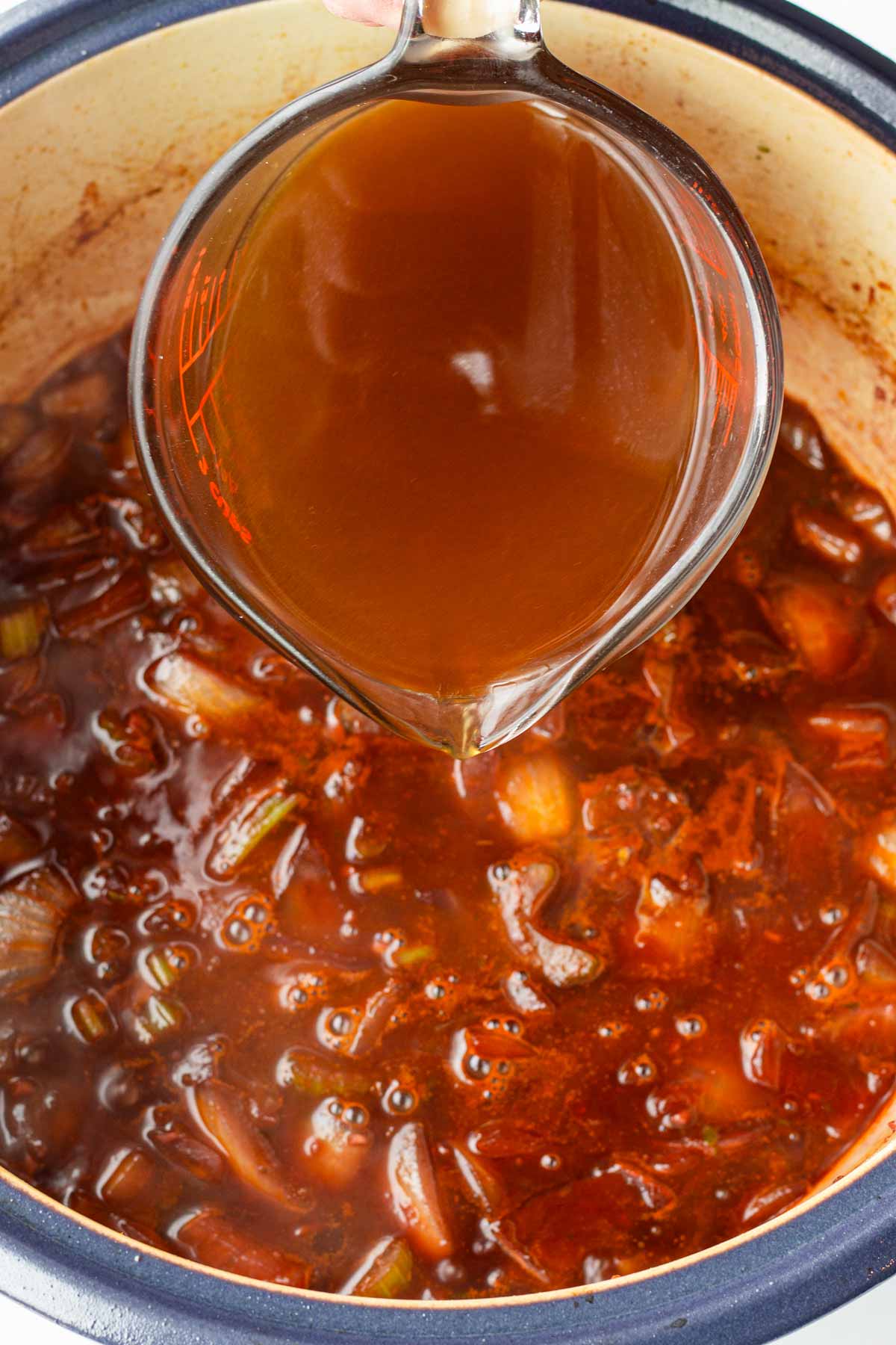 adding beef broth to the dutch oven