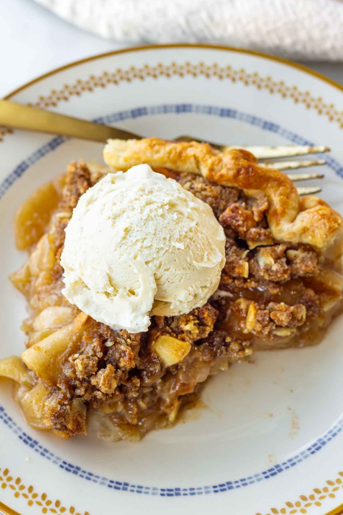 a sliced of apple crumble pie with ice cream on top