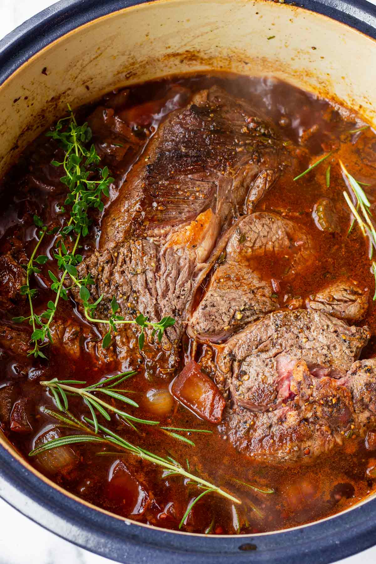 beef returned to the dutch oven with herb sprigs