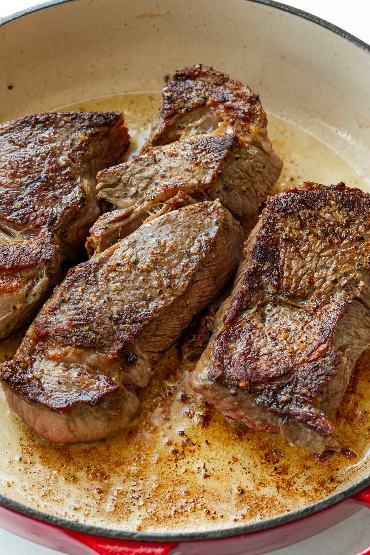 searing seasoned chuck roast cut into three parts