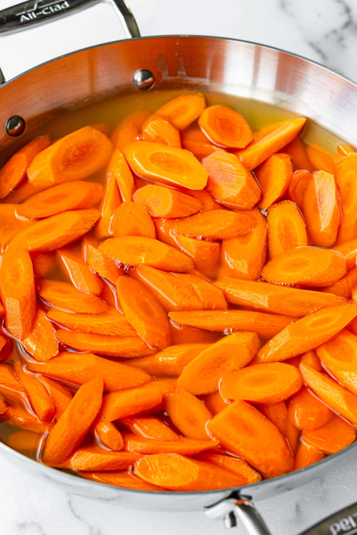 cooking the sliced carrots in broth in a pan