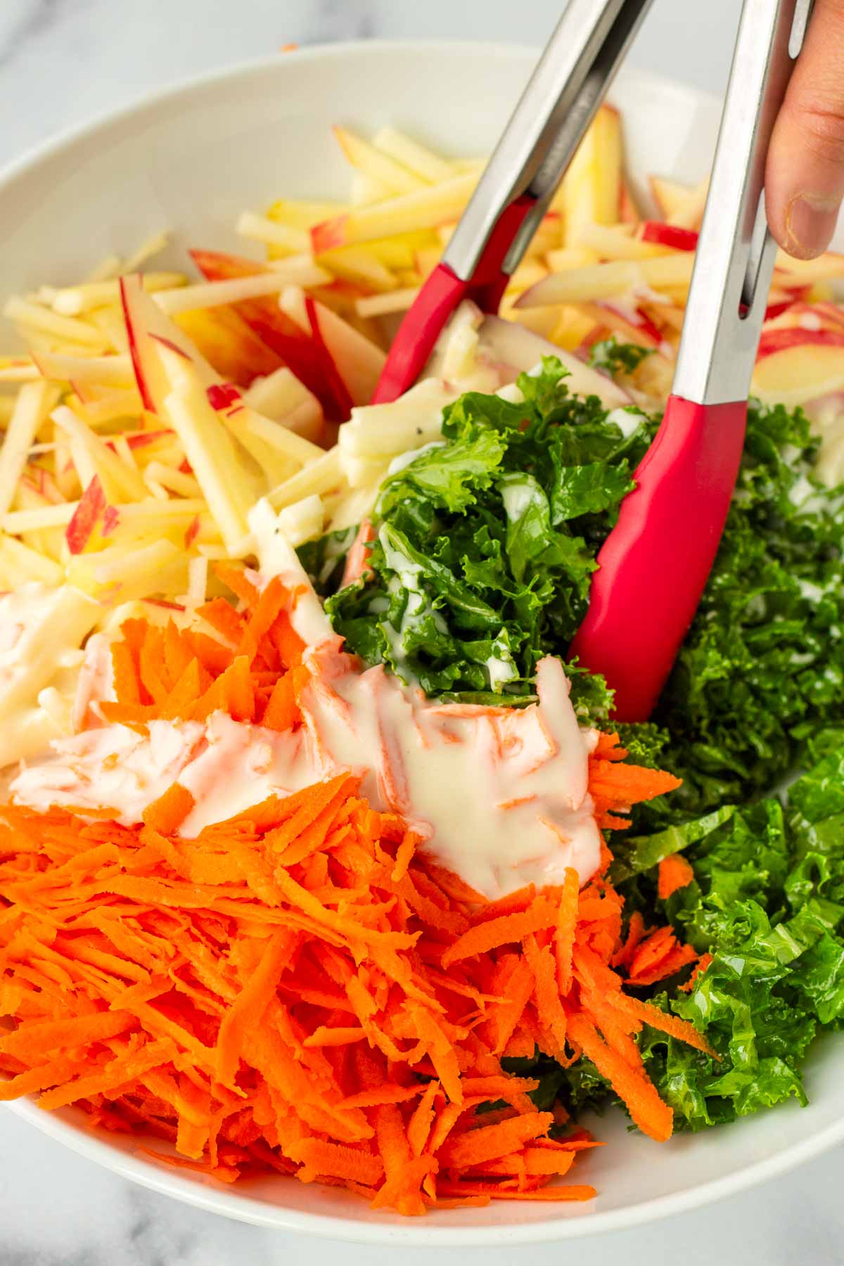 tossing the slaw ingredients together with tongs