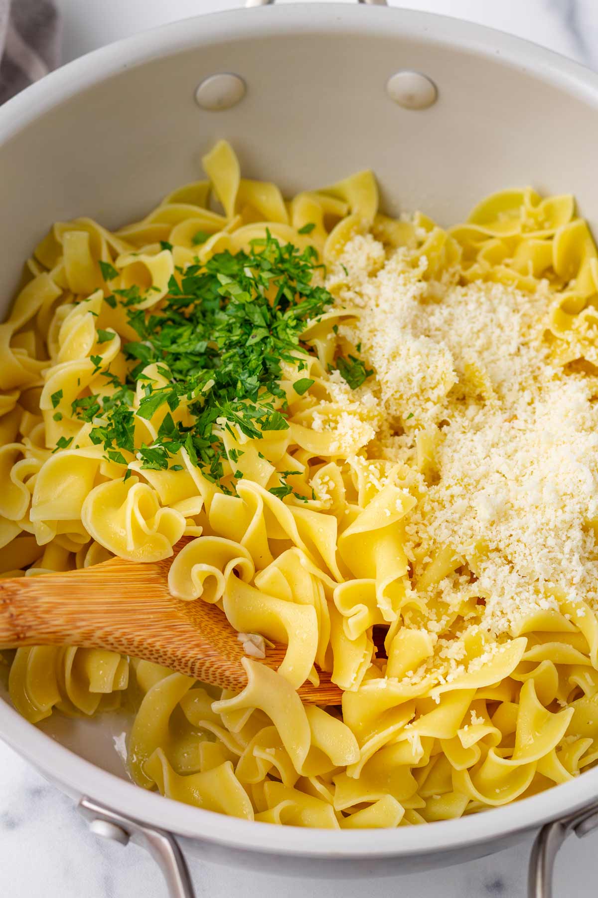 tossing noodles with cheese and parsley