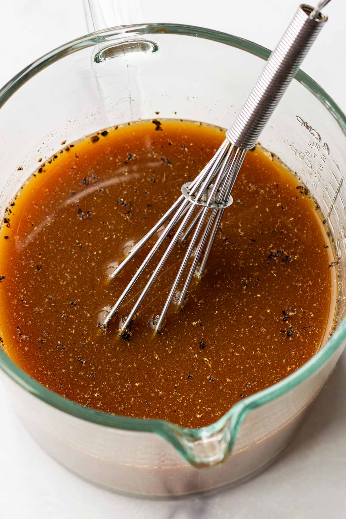 mixing the sauce cooking liquid in a measuring cup