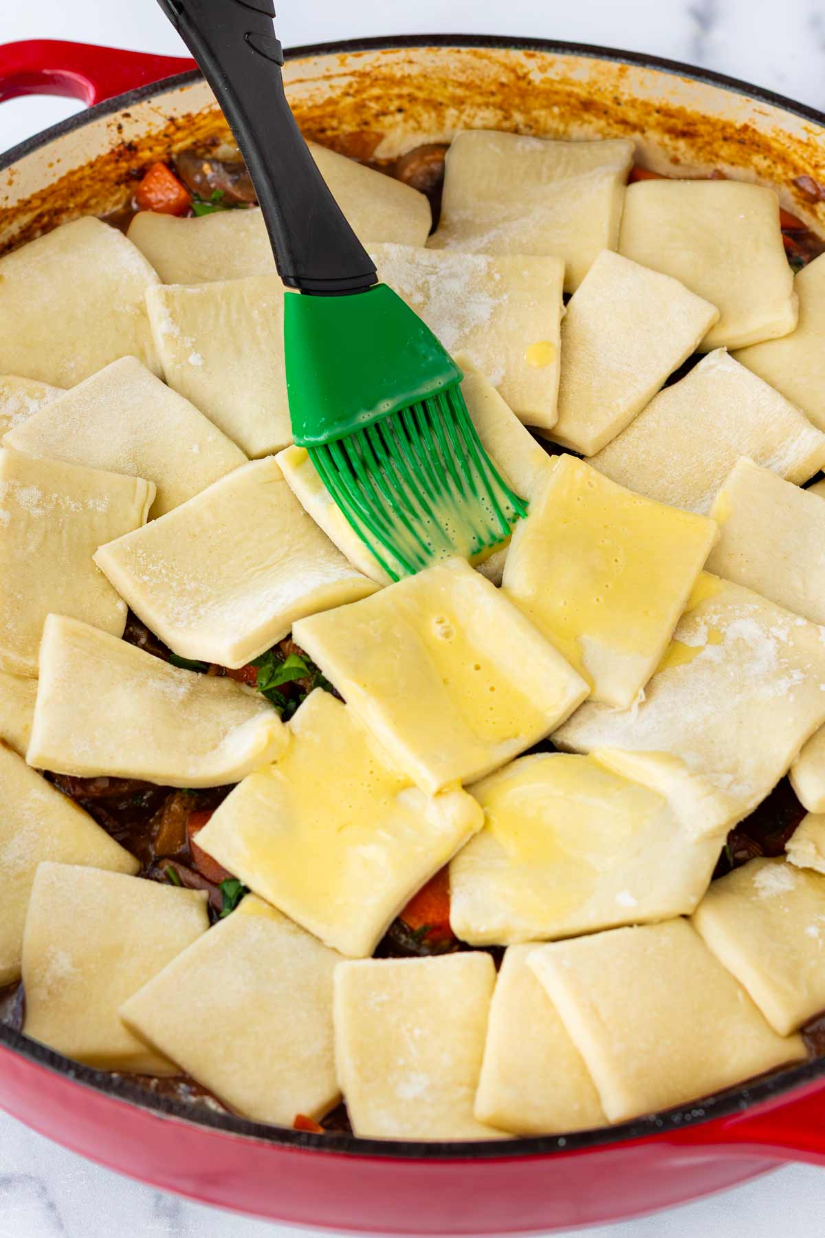 topping beef pot pie with puff pastry and brushing with egg wash
