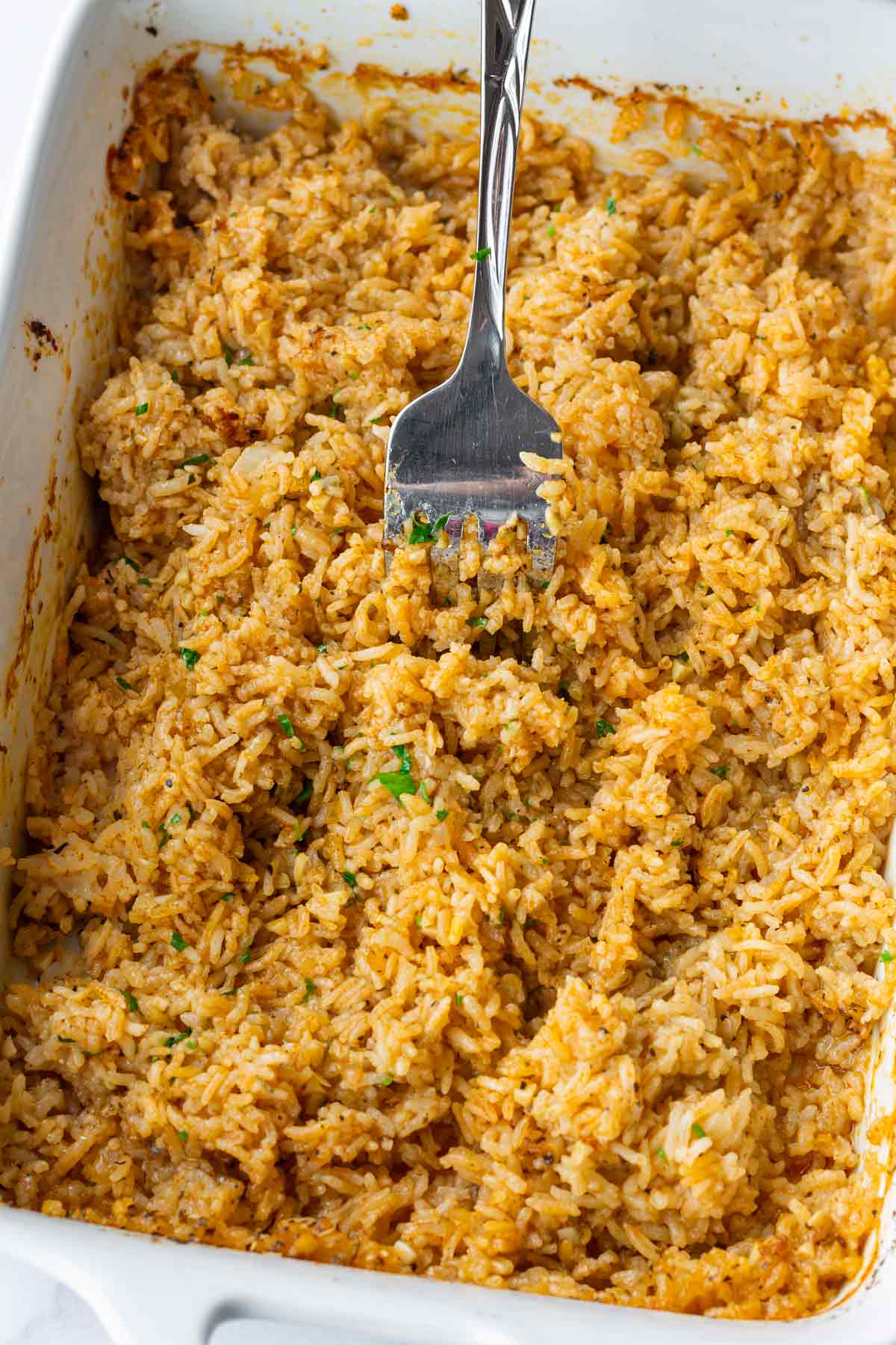 fluffing the rice with a fork in the pan