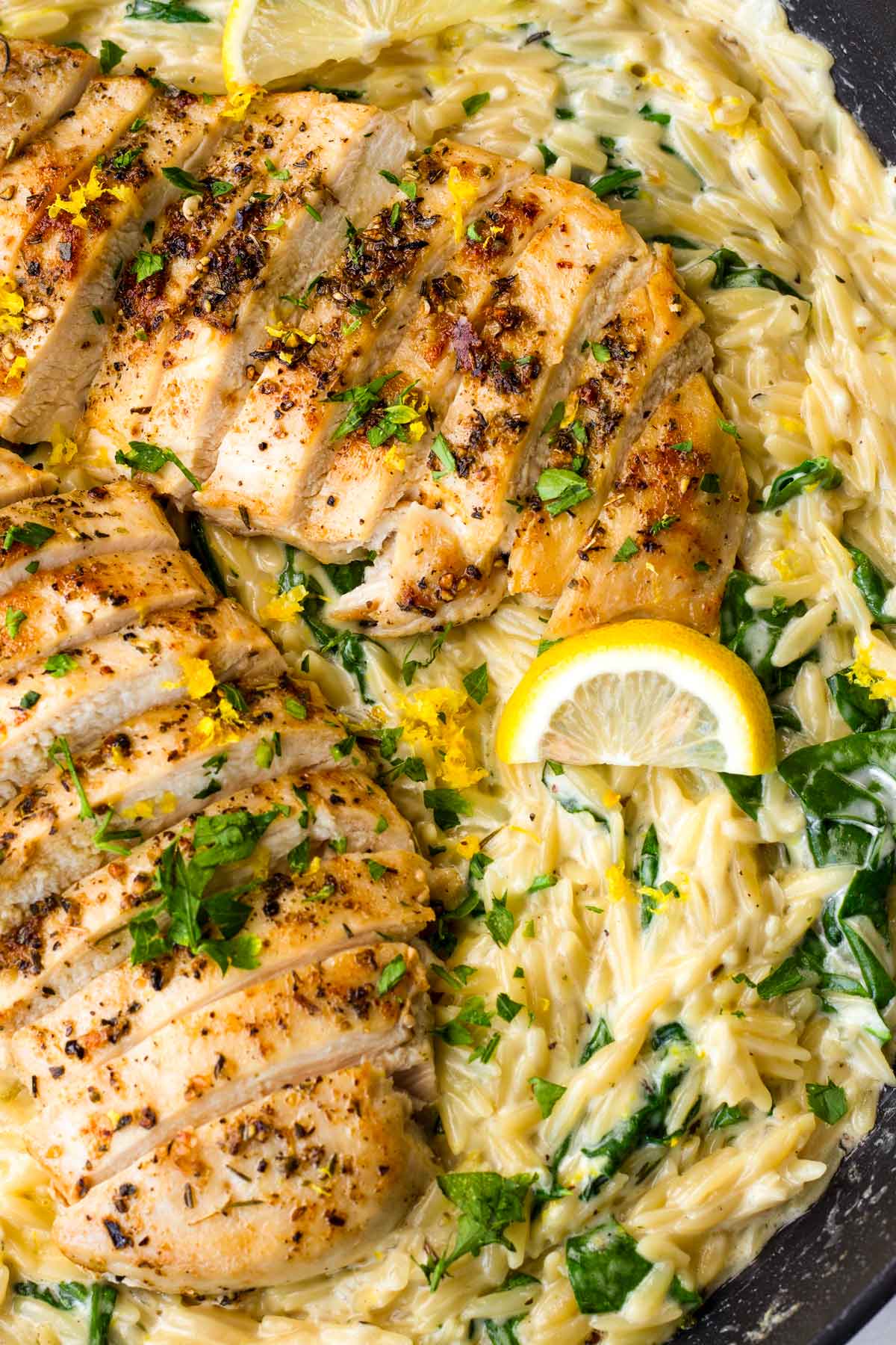 adding the cooked sliced chicken breast on top of lemon orzo